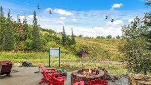 A patio with red Adirondack chairs, a fire pit, and a grill. - Storm Meadows, Ski in/out Mountain Retreat (Steamboat Springs)