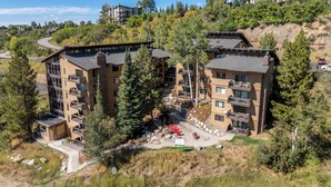 A multi-story building with balconies, surrounded by trees and a hilly landscape. - Storm Meadows, Ski in/out Mountain Retreat (Steamboat Springs)