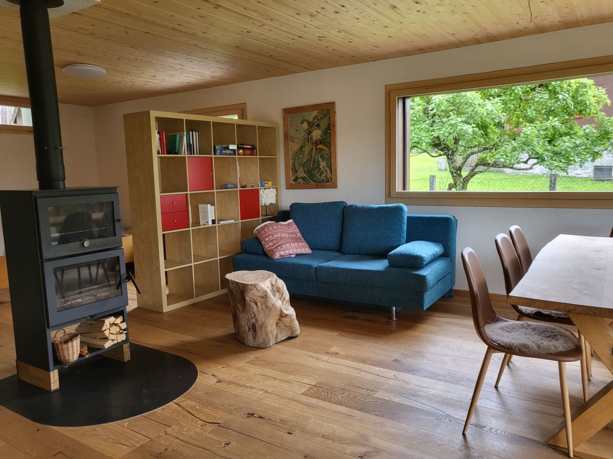 Un salon chaleureux avec une cheminée, un canapé bleu, une table à manger en bois et une bibliothèque.