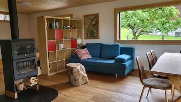 Un salon chaleureux avec une cheminée, un canapé bleu, une table à manger en bois et une bibliothèque.