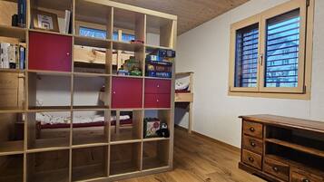 Une pièce avec une bibliothèque en bois, une fenêtre avec des stores et un petit bureau en bois.