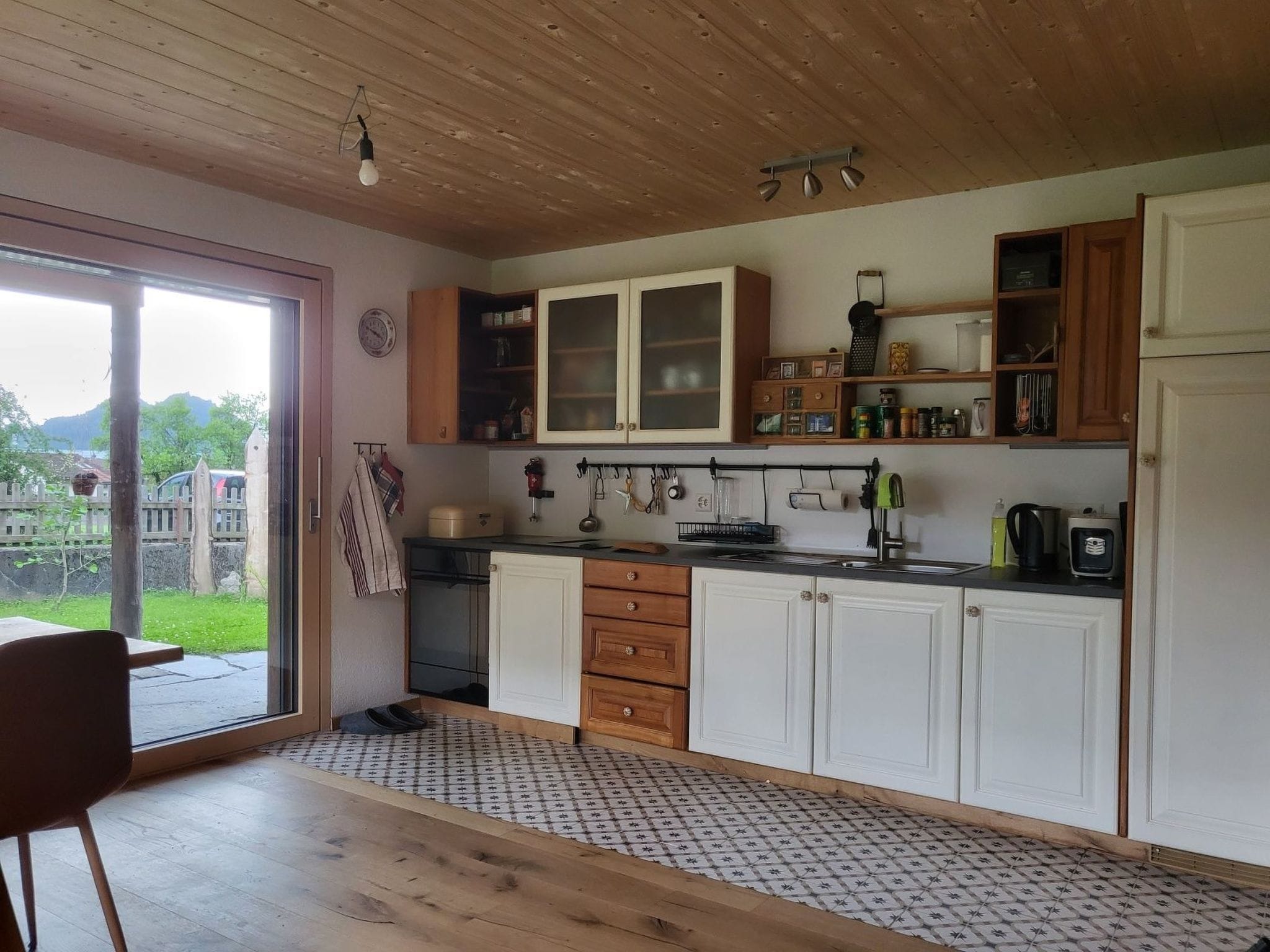 Eine Küche mit Holzschränken, einem Spülbecken und einem Fenster mit Blick auf einen Garten.