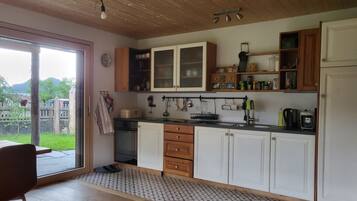Une cuisine avec des meubles de rangement en bois, un évier et une fenêtre donnant sur un jardin.