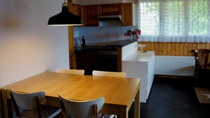 Eine kompakte Küche mit Holzausstattung, einem Herd und einem Essbereich mit Tisch und Stühlen.