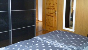 A bedroom with a bed, a wooden door, and a window.