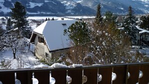 A snow-covered mountain landscape with a building featuring a sloped roof and a visible window.