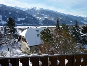 A snow-covered mountain landscape with a building featuring a sloped roof and a visible window.