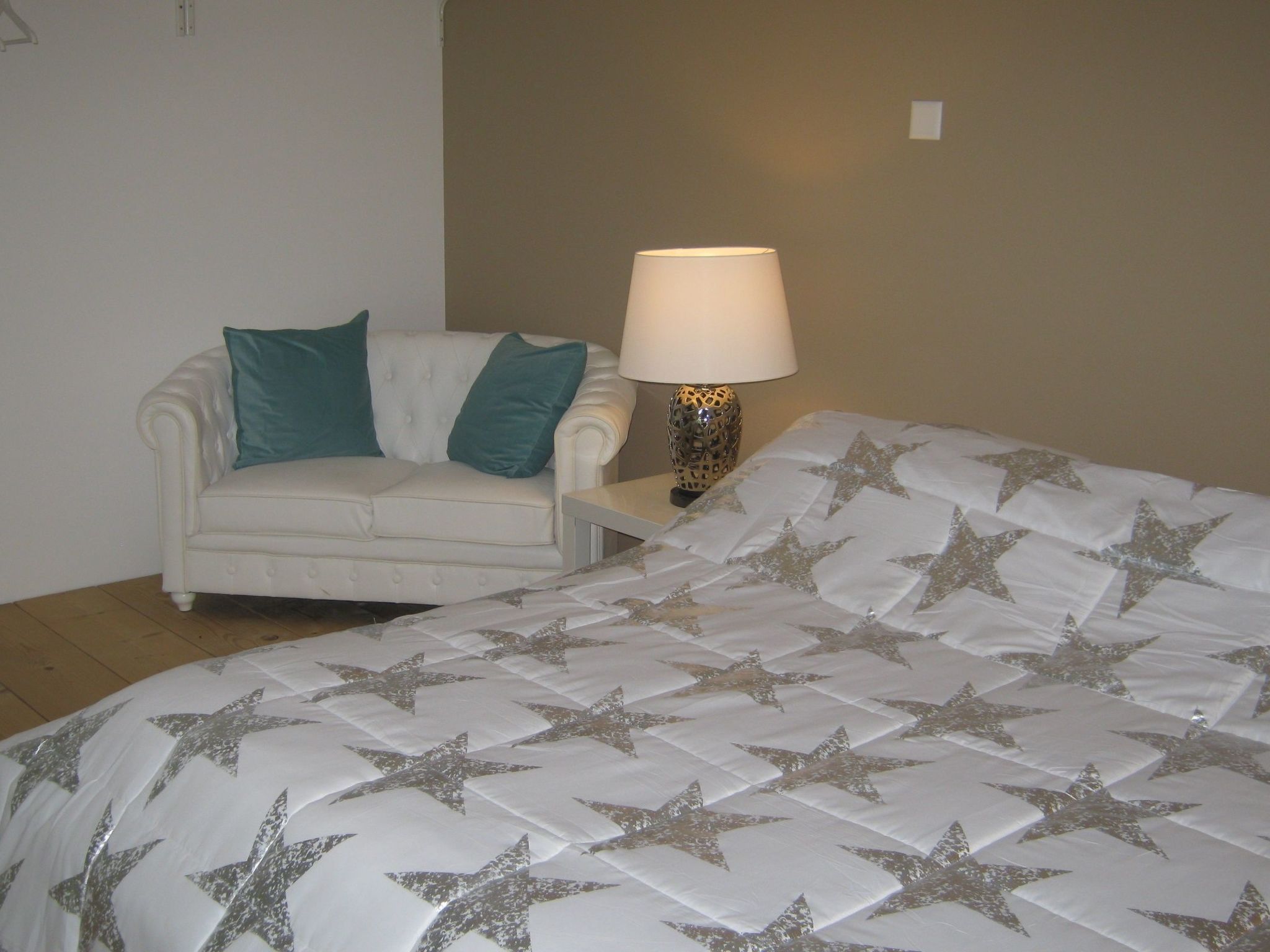 A bedroom with a bed, a chair, and a bedside lamp.
