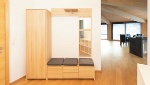 A room with a wooden bench, a wardrobe, and a dining area with a table and chairs.