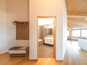 A modern interior with a wooden floor, a bathroom with a mirror and sink, and a small desk with a chair.