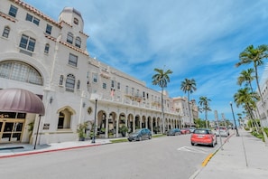 A multi-story hotel with a classic architectural style, featuring arched windows and a central courtyard with palm trees. - The Island Terrace Suite at Palm Beach Hotel (Palm Beach)