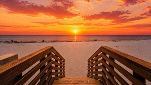 A wooden boardwalk leading to a beach with a sunset in the background. - The Island Terrace Suite at PBH w/ Valet Parking (Palm Beach)