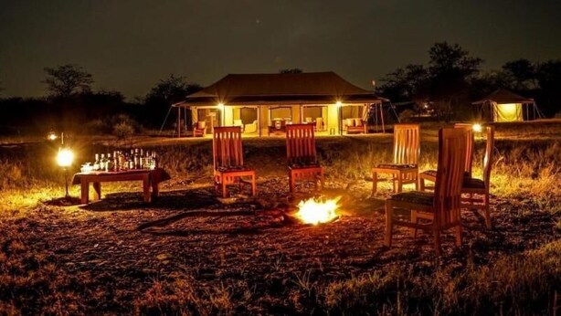 A house with a covered outdoor area, a fire pit, and several chairs.