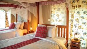 A room with two beds, a canopy bed, and a nightstand with a lantern.