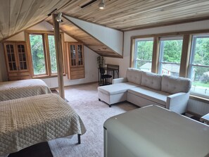 A bedroom with two beds, a sofa, a desk, and large windows with a view of greenery. - Lake Barkley Bridge House Cabin (Cadiz)