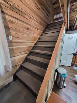 A wooden staircase with a metal trash bin and a door in the background. - Lake Barkley Bridge House Cabin (Cadiz)