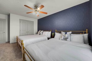 A bedroom with two beds, a ceiling fan, and a patterned wall.