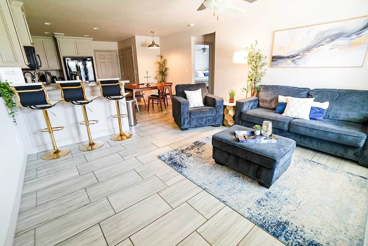 Un salon moderne avec un canapé gris, une table basse et un coin repas comprenant une table et des chaises.