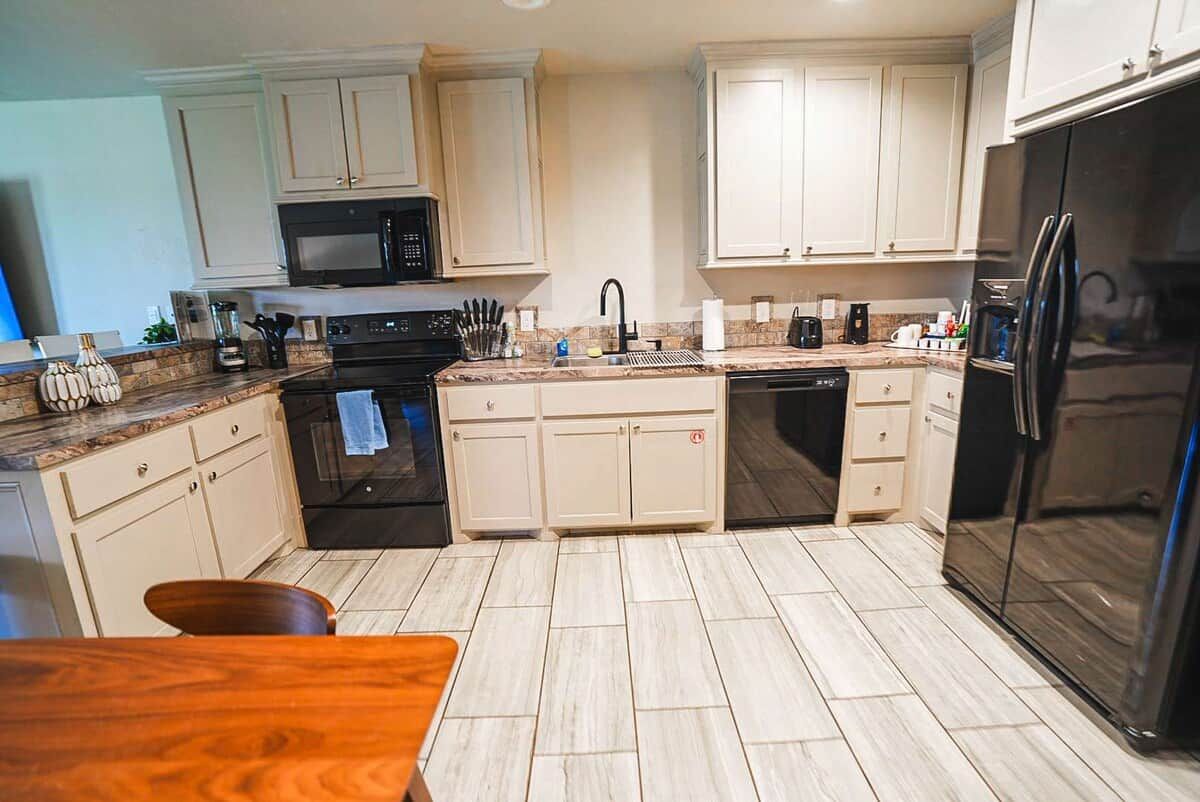 A kitchen with white cabinets, a black refrigerator, a microwave, and a dishwasher.