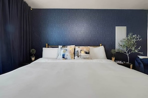 Une chambre d’hôtel avec un grand lit, un mur à motifs sombres et une plante en pot.