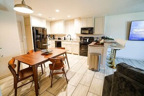 A modern kitchen with a dining table, chairs, a refrigerator, microwave, and a TV. - Family-Friendly 2BR,King bed @ Fort Sill, Lawton  #D (Elgin)