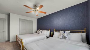 Une chambre d’hôtel avec deux lits, un ventilateur de plafond, un mur décoré d’un motif et une porte.
