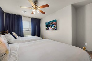 A hotel room with two beds, a ceiling fan, a large window with curtains, and a wall-mounted television. - Family-Friendly 2BR,King bed @ Fort Sill, Lawton  #D (Elgin)