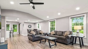 Ein geräumiges Wohnzimmer mit einem dunkelbraunen Ledersofa, einem Couchtisch und einem Deckenventilator.