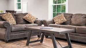 Ein Wohnzimmer mit einem braunen Ledersofa, einem Holztisch und dekorativen Kissen.