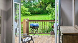 Ein Balkon mit Grill, Stuhl und Blick auf einen grünen Garten.
