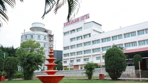 Un hotel con un letrero que dice 'Sivaranjani Hotel', un edificio de varios pisos y una fuente al frente.