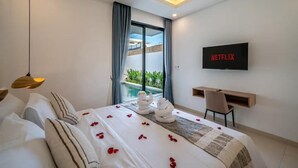 Habitación de hotel moderna con cama, escritorio, televisor y vista a una piscina.