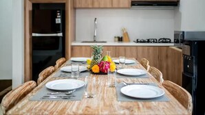 Una mesa de comedor con platos, cubiertos y un centro de mesa con frutas y flores.