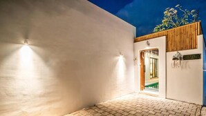 Exterior de un edificio moderno con entrada pavimentada, techo de listones de madera y un letrero que indica un restaurante.