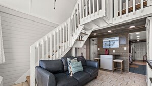 Ein modernes Interieur mit einem schwarzen Ledersofa, einer weißen Treppe und einer Küchenzeile.
