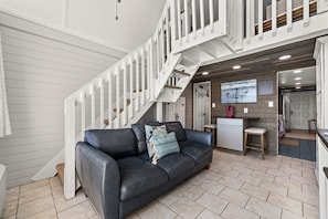 Ein modernes Interieur mit einem schwarzen Ledersofa, einer weißen Treppe und einer Küchenzeile.