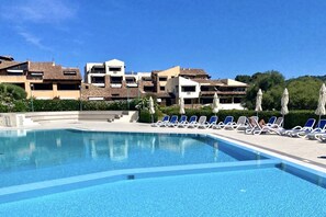 A swimming pool with lounge chairs and umbrellas, surrounded by multi-story buildings with balconies. - P.Rotondo1 A307 S SEA VIEW (Porto Rotondo)