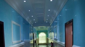 A long, narrow hallway with blue walls, a marble floor, and a door at the end. - Mile Stone Hotel & Suites (Lekki)