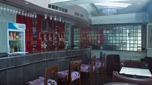 A bar area with a Solstar refrigerator, wooden chairs with floral upholstery, and a curved counter. - Mile Stone Hotel & Suites (Lekki)
