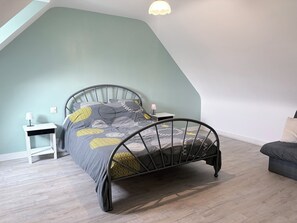 A bedroom with a bed, bedside tables, a lamp, and a chair. - Ty Ar Méné Vacation Rental (Lohuec)