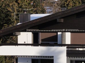 Een modern gebouw met een schuin dak, schoorsteen en garagepoort.