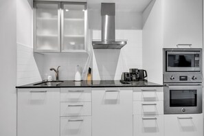A modern kitchen with a stainless steel range hood, a microwave, and an oven. - Midtown Vale Hotel (Toronto)