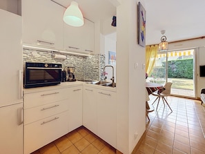 Een moderne keuken met witte kastjes, een ingebouwde oven en een koffiezetapparaat.