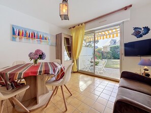 A dining area with a table, chairs, a vase of flowers, a painting, and a sliding glass door leading to an outdoor patio. - Salicornia by Interhome (Carnac)