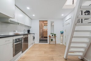 Eine moderne Küche mit Edelstahlgeräten, Holzboden und einer Treppe, die zum Schlafzimmer auf dem Dach führt.