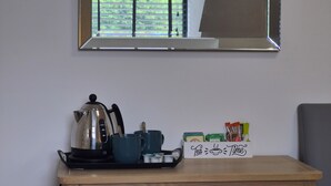 Una kitchenette con una tetera, tazas y bolsitas de té sobre una bandeja.