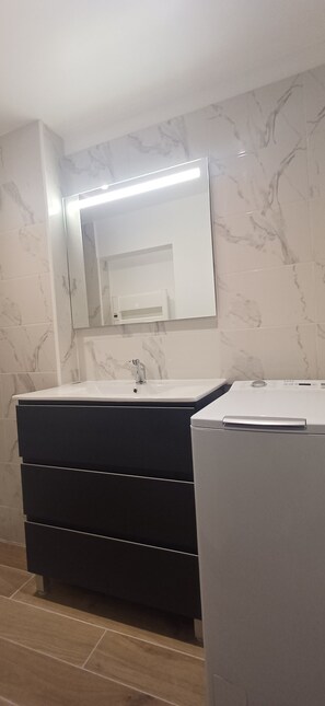 Ein Badezimmer mit einem Waschbecken-Doppelplatz, einem Spiegel und einer Waschmaschine.