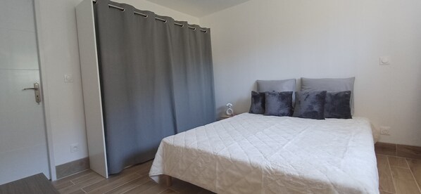 Ein Schlafzimmer mit einem Bett, grauen Vorhängen und einem Nachttisch.