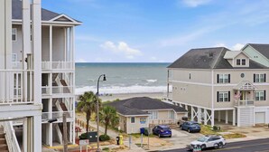 Un quartier résidentiel situé sur la côte, avec des immeubles à plusieurs étages, une vue sur la plage et des voitures garées.