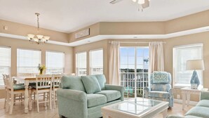 Un salon spacieux comprenant un canapé, des fauteuils, une table basse en verre et un coin repas avec une table et des chaises.
